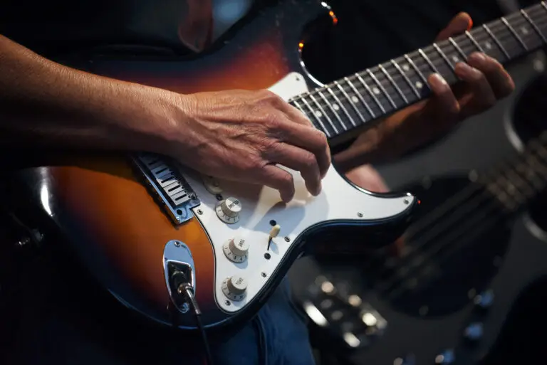 Man's hands playing on an electric guitar in a band on stage, entertainment of a guitarist artist with his music instrument